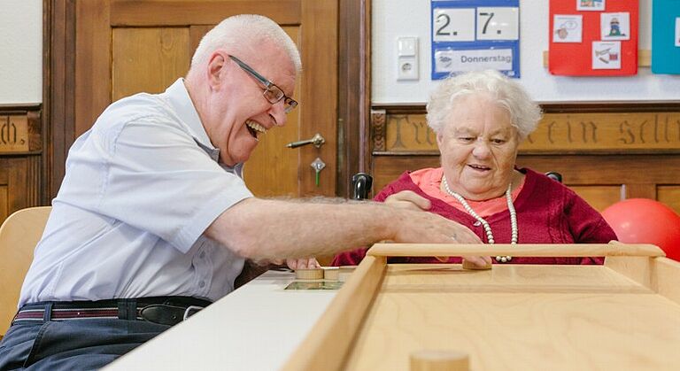 Zwei Senioren mit Behinderung spielen ein Spiel in der Seniorentagesstätte Obernzenn